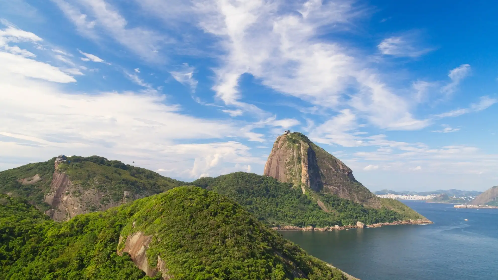 View of Sugarloaf Mountain highlighting its lush green slopes and a touch of sea.