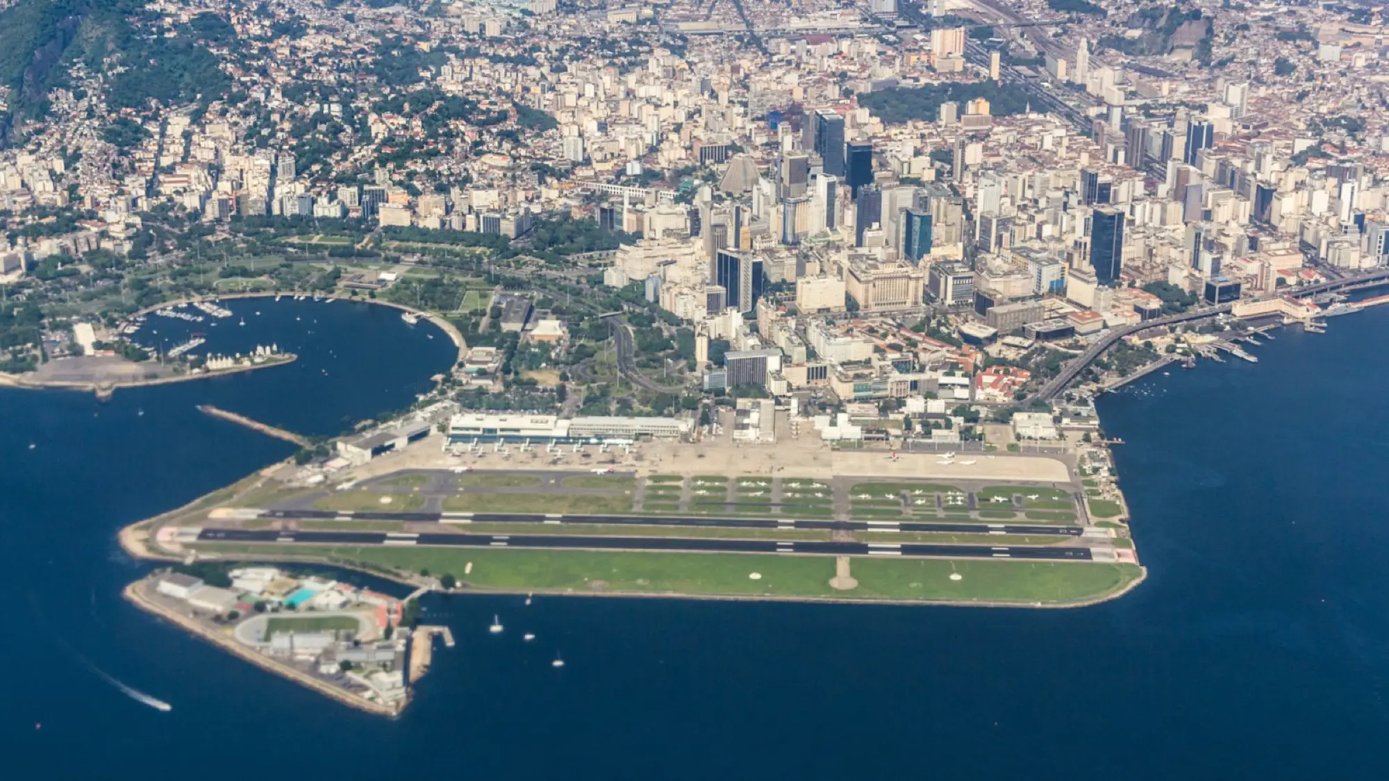 Aerial view of Rio de Janeiro, showcasing downtown buildings, waterfront, and the airport near the bay.