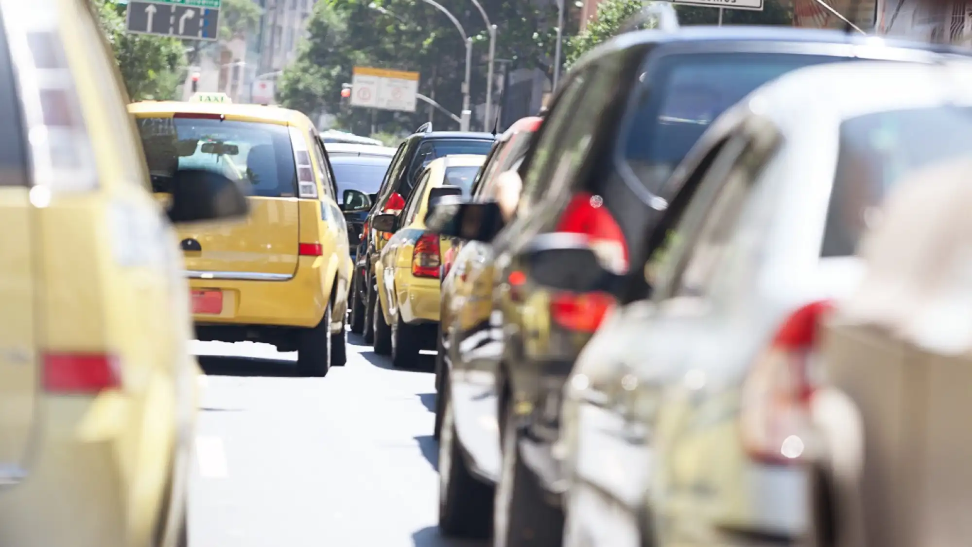 A traffic jam in Rio de Janeiro with multiple yellow taxis and cars stuck in congestion on a busy city street.