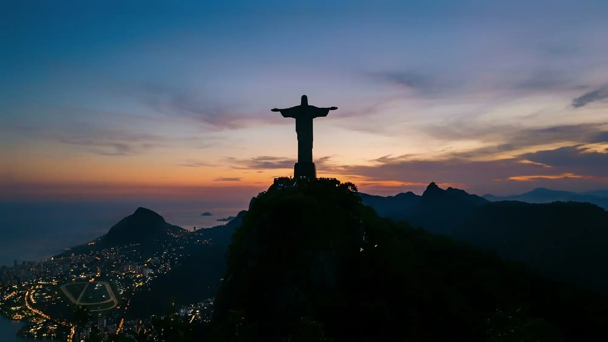 Le Christ Rédempteur en silhouette au sommet, au crépuscule, son contour lisible depuis l’autre bout de la ville
