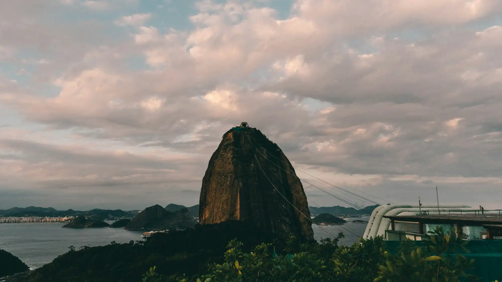 Le Pain de Sucre au crépuscule vu du Morro da Urca, les câbles du téléphérique montant vers le sommet et la station à côté